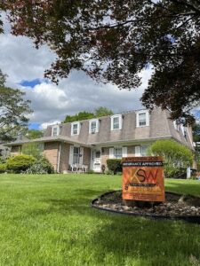 A KSW Construction lawn sign in front of a house that reads: "Another job insurance approved."