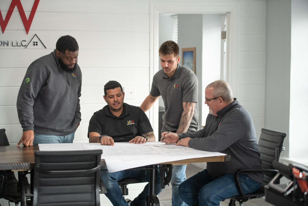 The KSW home improvement team strategies a client's proposal at a table.