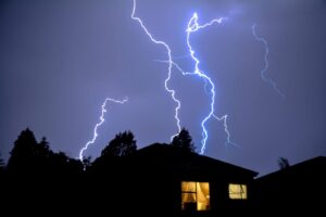 Lightning strikes a house silhouetted against the night sky