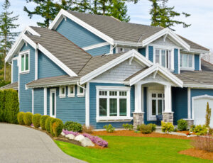 House with blue siding and gray roof with a green lawn out front.