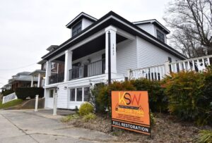 full restoration house on a main street with new white siding and black railings on deck