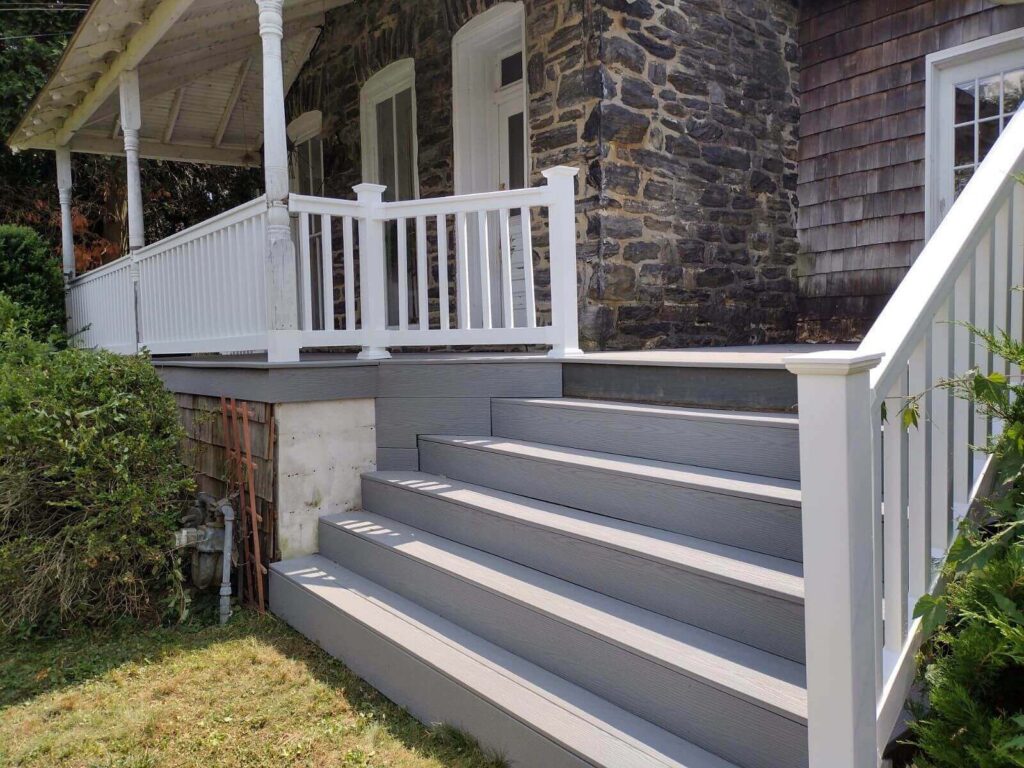 Steps leading up to a deck on an old stone house with a shaded porch