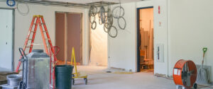 An office remodel in progress with a ladder and construction equipment in an empty room