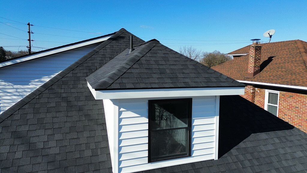 A black shingled roof with a white dormer