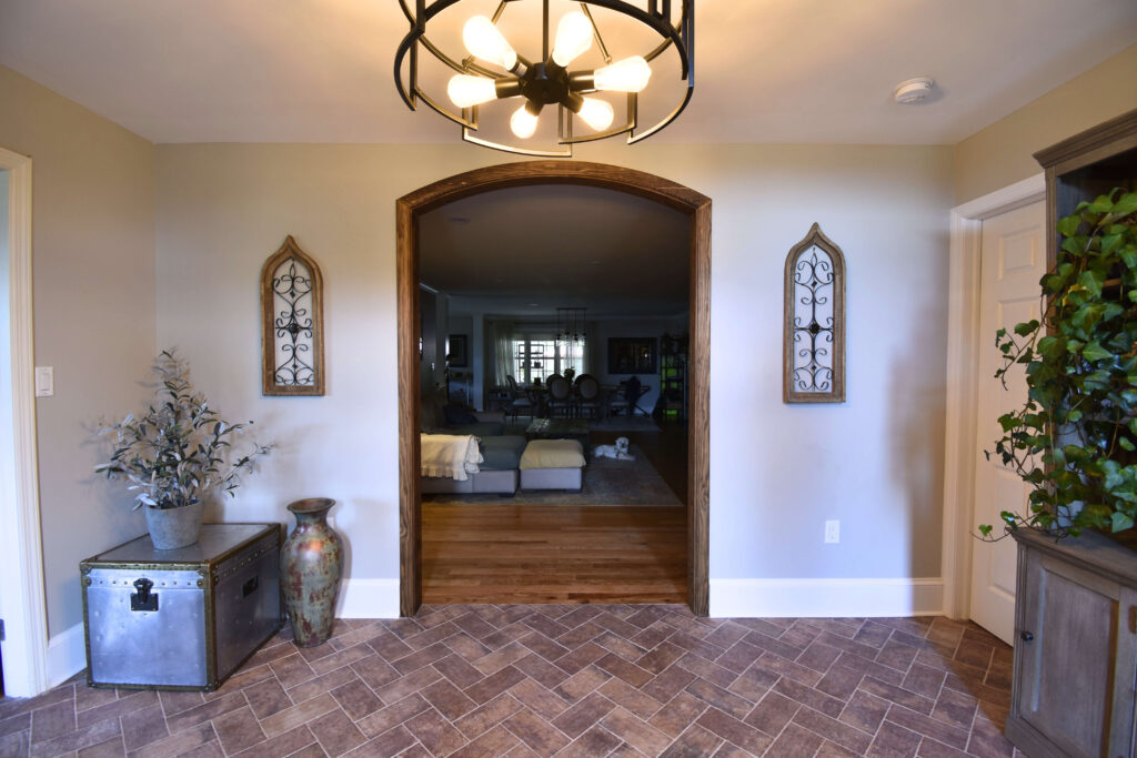 Finished residential front room home remodel straight on with wood trim around an archway and an industrial light fixture hanging from the ceiling