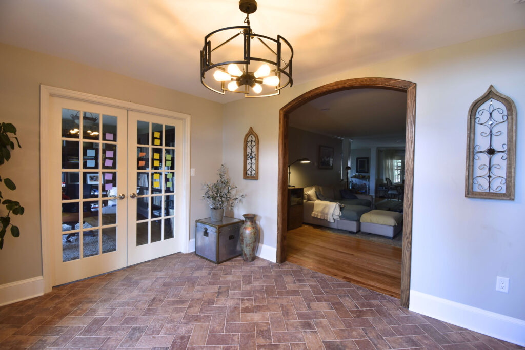 Finished residential front room home remodel at an angle with wood trim around an archway and glass doors leading to a music studio
