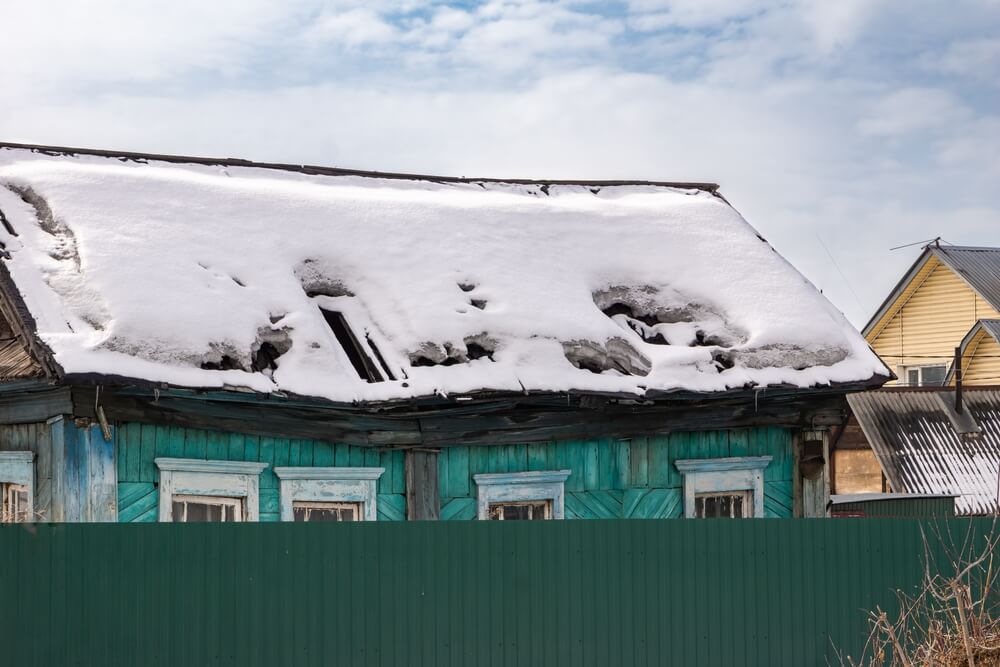 An old roof sagging under the weight of heavy snow damage