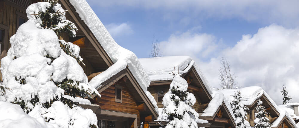 Wooden cabins with snow piled on their roofs