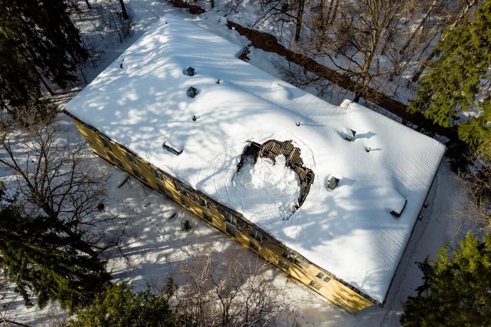 Showing how snow impacts your roof with a collapsed section on a commercial building covered in snow
