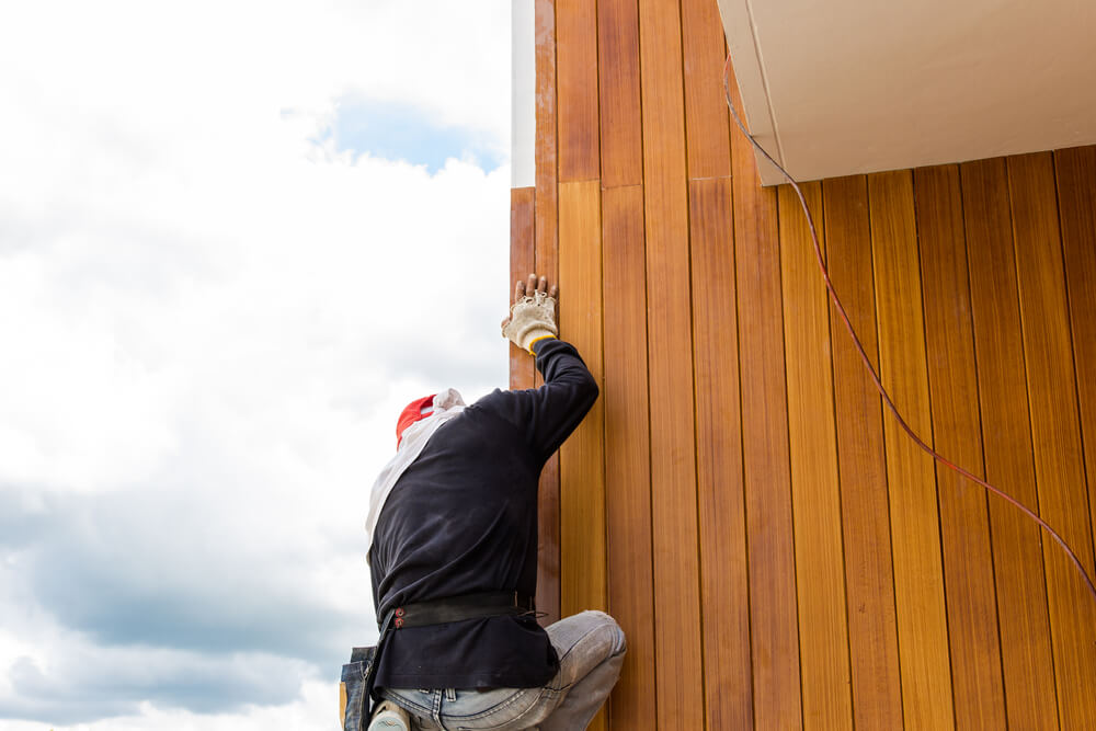 Man installing fiber cement siding on a house