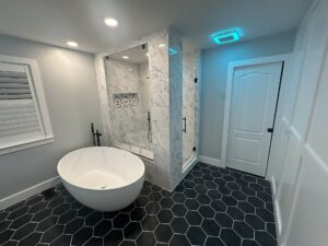 Bathroom remodel with a black tiled floor and white tub