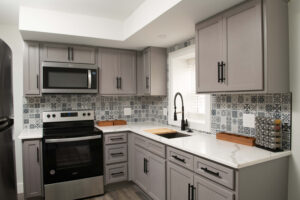 Kitchen remodel with a gray tiled backsplash and gray cabinets