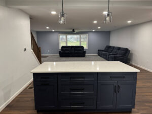 Kitchen and basement remodel from general contractors in Bucks County, PA. A navy blue counter, and past it is a window and two couches