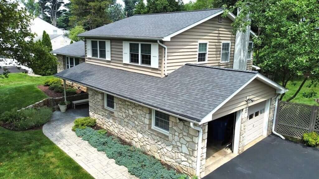A house showing siding vs cladding. It has tan siding on the top and stone cladding on the bottom